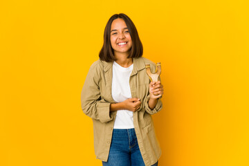 Young hispanic woman holding a slingshot laughing and having fun.