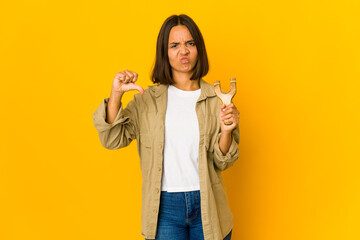 Young hispanic woman holding a slingshot showing a dislike gesture, thumbs down. Disagreement concept.