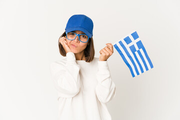 Young hispanic mixed race woman holding a greece flag covering ears with hands.