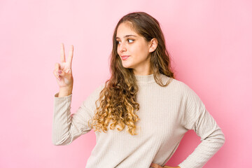 Young caucasian woman joyful and carefree showing a peace symbol with fingers.