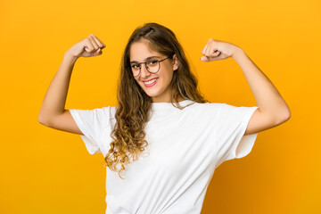 Young caucasian woman showing strength gesture with arms, symbol of power