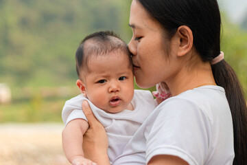Young Asian mother holding little daughter in the park, Mother play enjoying with her cute baby girl  outdoor, copy space
