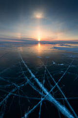 Baikal lake in winter with transparent cracked blue ice. Solar halo effect at sunrise. Baikal,...