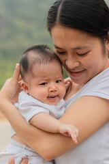 Young Asian mother holding little daughter in the park, Mother play enjoying with her cute baby girl  outdoor, copy space
