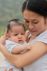 Young Asian mother holding little daughter in the park, Mother play enjoying with her cute baby girl  outdoor, copy space
