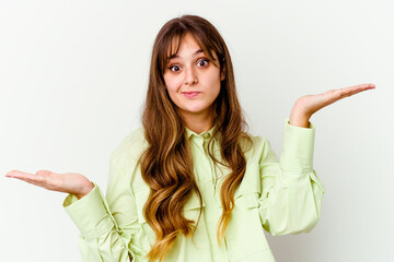 Young caucasian cute woman isolated on white background confused and doubtful shrugging shoulders to hold a copy space.