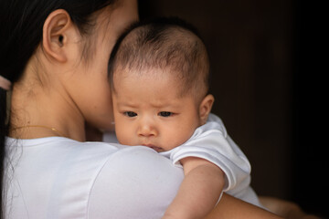 Mother was holding the baby with dark background
