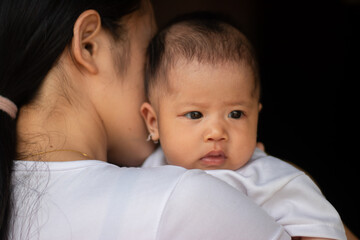 Mother was holding the baby with dark background
