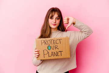 Young caucasian woman holding a Protect our planet placard isolated showing a dislike gesture, thumbs down. Disagreement concept.