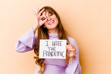 Fototapeta na wymiar Young caucasian woman holding a I hate the pandemic placard isolated excited keeping ok gesture on eye.