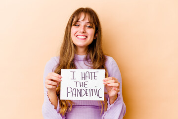 Young caucasian woman holding a I hate the pandemic placard isolated laughing and having fun.