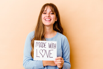 Young caucasian woman holding a made with love placard isolated laughing and having fun.