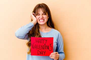 Fototapeta na wymiar Young caucasian woman holding a Happy Valentines day isolated covering ears with hands.