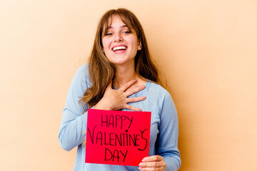 Fototapeta na wymiar Young caucasian woman holding a Happy Valentines day isolated laughs out loudly keeping hand on chest.