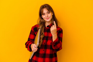 Naklejka premium Young caucasian woman holding a laptop isolated pointing with finger at you as if inviting come closer.