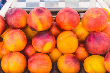 Heap of juicy fresh nectarine on market background