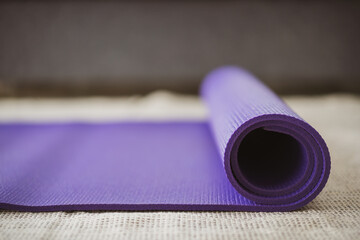 Rolled purple yoga exercise mat on the floor