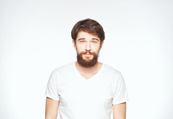 Fototapeta premium a man with a beard gestures with his hands on a light background Copy Space man