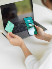 Female hand using online banking application on smartphone and holding credit card
