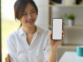 Smiling female showing mock up smartphone screen to camera