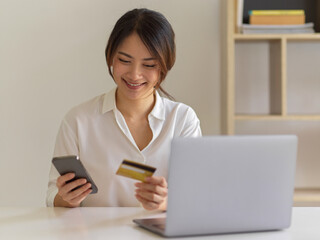 Fototapeta premium Female feeling happy when she shopping online on smartphone and paying with credit card