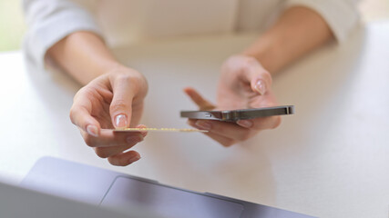 Fototapeta premium Female hands holding smartphone and credit card to online payment on workspace