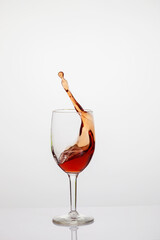 Splash of red wine in glass on white background.