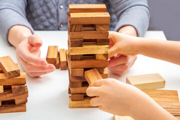 Hands grandmother and grandson play board game with wooden blocks. Concept of family relationships,...
