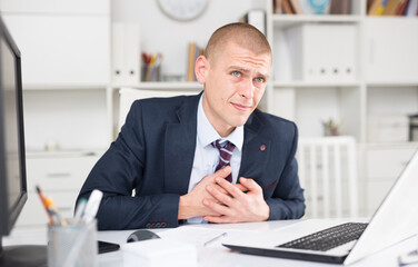 Male working in the company's office felt pain in the heart area and put his hands on his chest