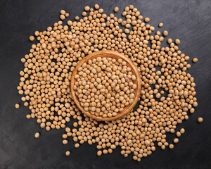 Soyabeans soya beans in wooden bowl flowing over black slate stone background copy text space flat lay top view