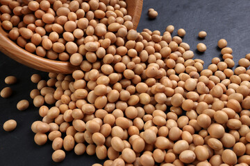 Soyabeans soya beans in wooden bowl flowing over black slate stone background copy text space flat lay top view