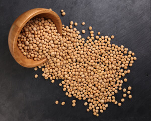 Soyabeans soya beans in wooden bowl flowing over black slate stone background copy text space flat lay top view