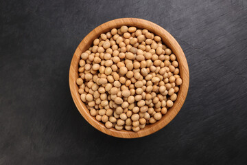 Soyabeans soya beans in wooden bowl over black background copy text space flat lay top view