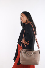 Young woman in casual outfit with stylish bag on white background.