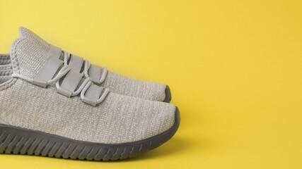 Stylish gray unisex sneakers on a yellow background. Colors 2021.