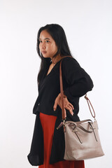 Young woman in casual outfit with stylish bag on white background.
