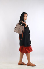 Young woman in casual outfit with stylish bag on white background.