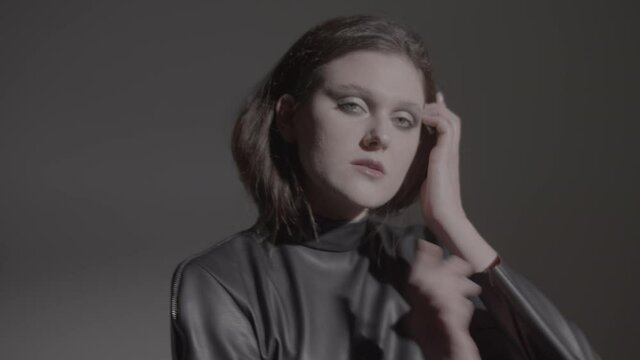 Dark hair woman posing in the black dress in the studio lights. Young attractive woman wearing a black dress. Ungraded video.