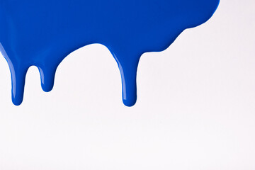 Navy blue liquid drops of paint color flow down on isolated white background. Abstract sapphire backdrop