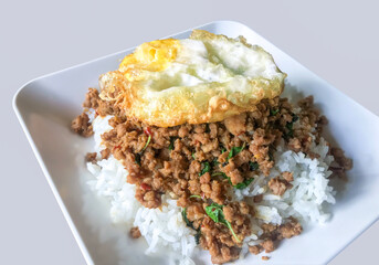 Fried basil leaves with pork and fried egg on rice Thai food grey background