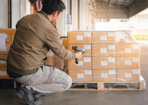 Asian Warehouse Worker Scanning Bar Code Scanner On Package Box. Computer Tools For Warehouse Inventory Management.	