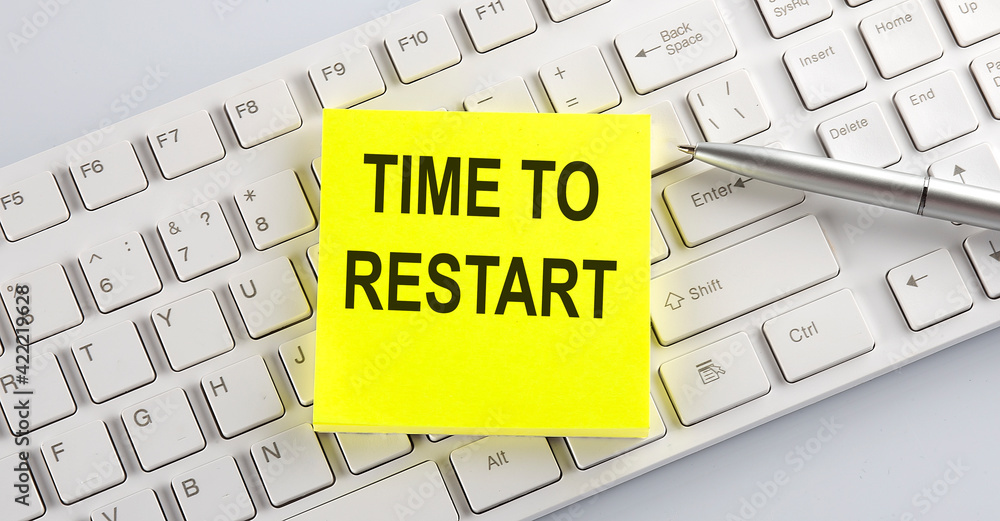 Poster words time to restart written on stickers on a computer keyboard