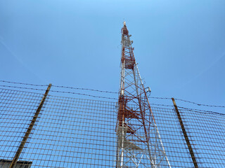 View of an old red and white telecommunication tower looking up from ground level