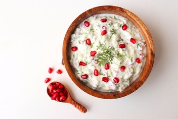 Indian Fresh sauce or condiment called Raita. Yogurt mixed with grated cucumber, onions,  pomegranate and spices. Garnished with fresh coriander. Copy space.