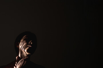 Human trafficking. Female slavery. Forced labour. Art portrait of suffering hostage woman silhouette with hands on throat abstract shadow on face isolated on black night empty space background.