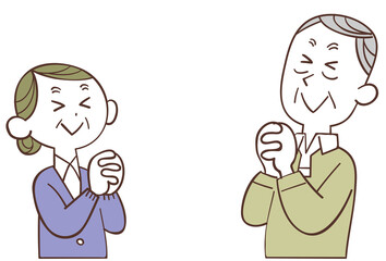 向かい合い目を瞑って祈るシニアの夫婦
