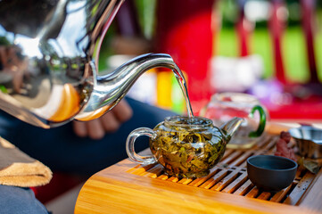 Traditional Chinese tea ceremony. Hot water pouring into a glass teapot with green tea leaves of Chinese oolong tea in it. - 422225003
