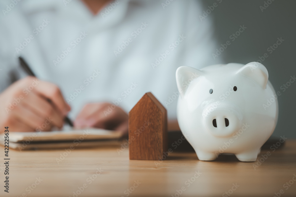 Aufkleber piggy bank with man doing finances and calculate on desk about cost at home office..concept of save,