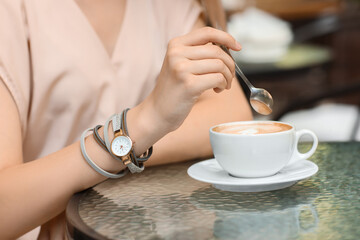 Woman with stylish wrist watch sitting in cafe