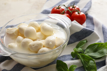 Bowl with mozzarella cheese on grunge background, closeup